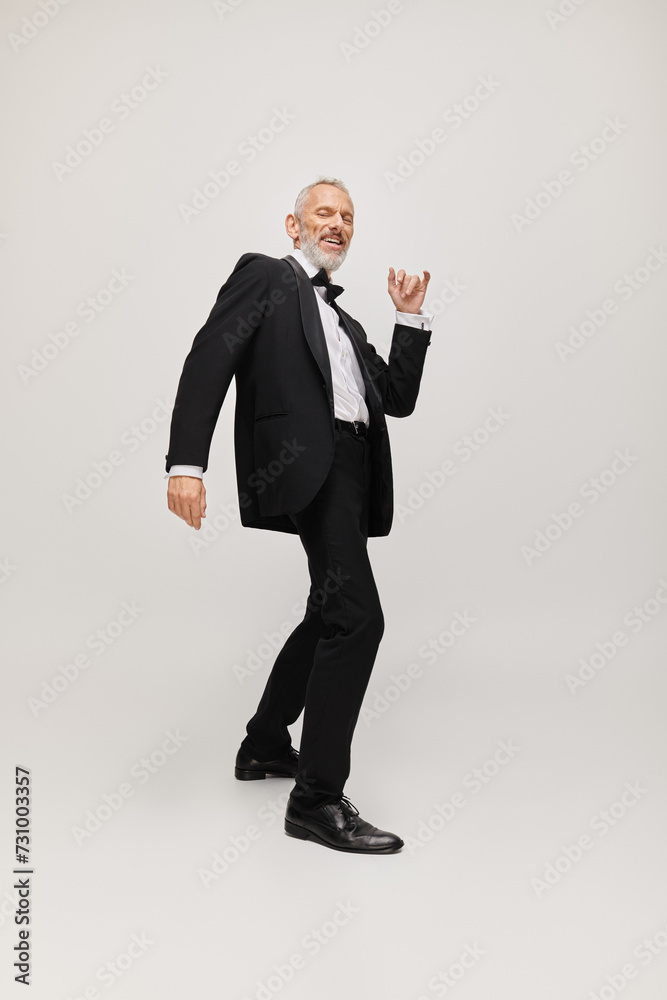 cheerful attractive gray bearded man with dapper stylish tuxedo dancing and smiling at camera cheerful attractive gray bearded man with dapper stylish tuxedo dancing and smiling at camera