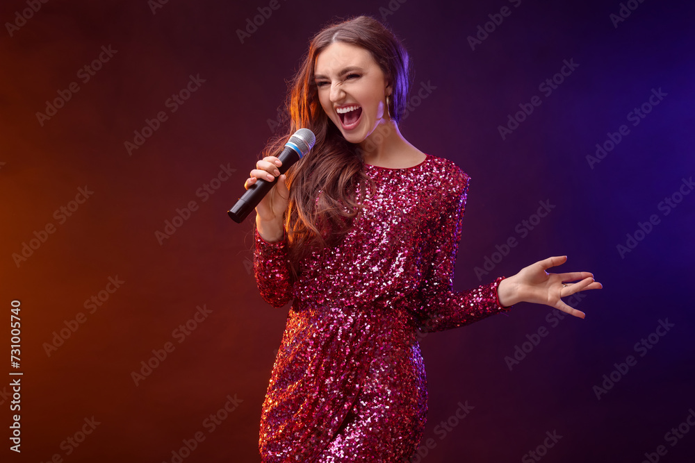 Emotional woman with microphone singing in color lights Emotional woman with microphone singing in color lights
