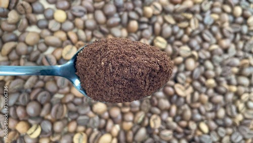 Freshly ground fragrant coffee powder in a spoon and coffee beans rotating in the background. Brew aromatic morning coffee. Preparing a hot invigorating drink. Arabica Cup. Flat layout.