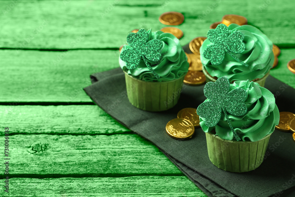 St. Patrick's day. Tasty cupcakes with clover leaf toppers and cream on green wooden table, closeup. Space for text