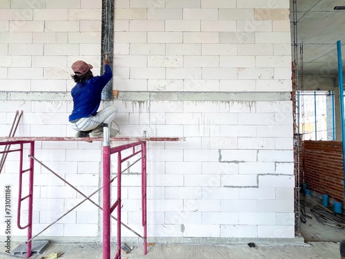 A bricklayer is laying bricks on a bathroom wall.