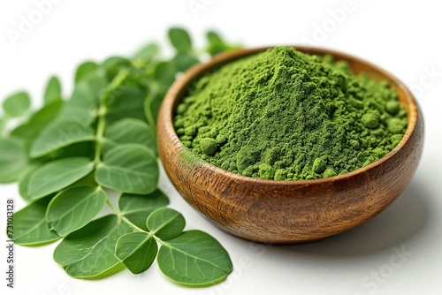Close-up of Moringa powder in wooden bowl and leaves isolated on white background.