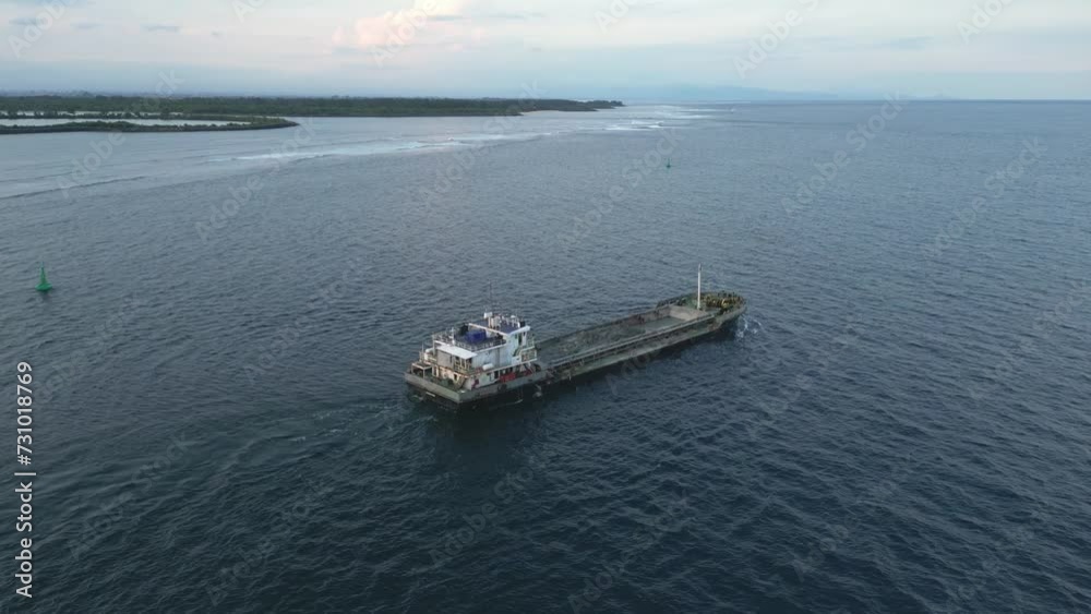 Aerial view of an old small freighter moving through the bay in the evening at sunset. Aerial view of an old small freighter moving through the bay in the evening at sunset.