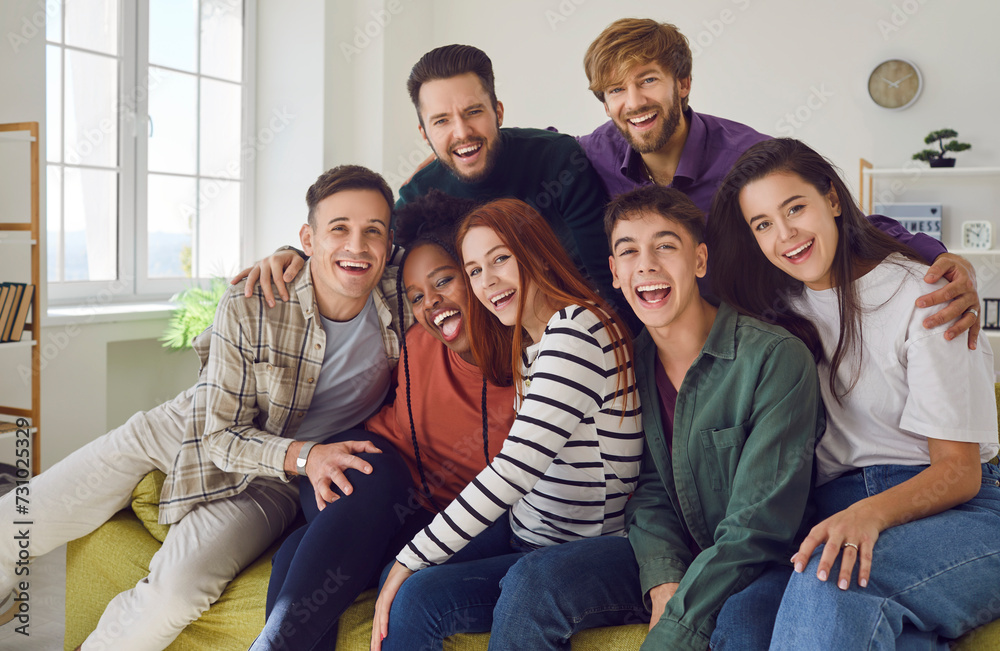 Group of young people sits on a sofa at home together, sharing moments of laughter and happiness. Portrait of a diverse camaraderie of friends, smiling and looking into the camera. Group of young people sits on a sofa at home together, sharing moments of laughter and happiness. Portrait of a diverse camaraderie of friends, smiling and looking into the camera.