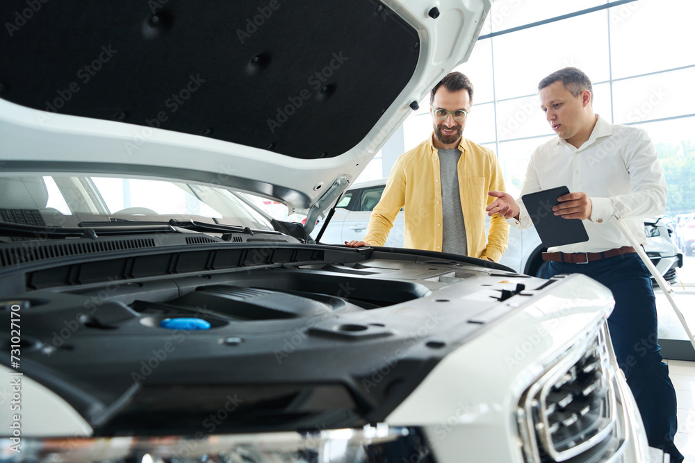 Consultant manager presents a popular car model to a man Consultant manager presents a popular car model to a man