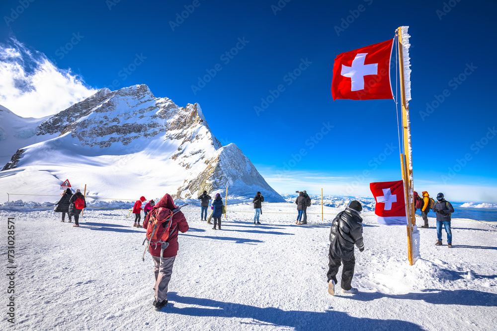 Tourists in front of Swiss flag on Jungfraujoch peak