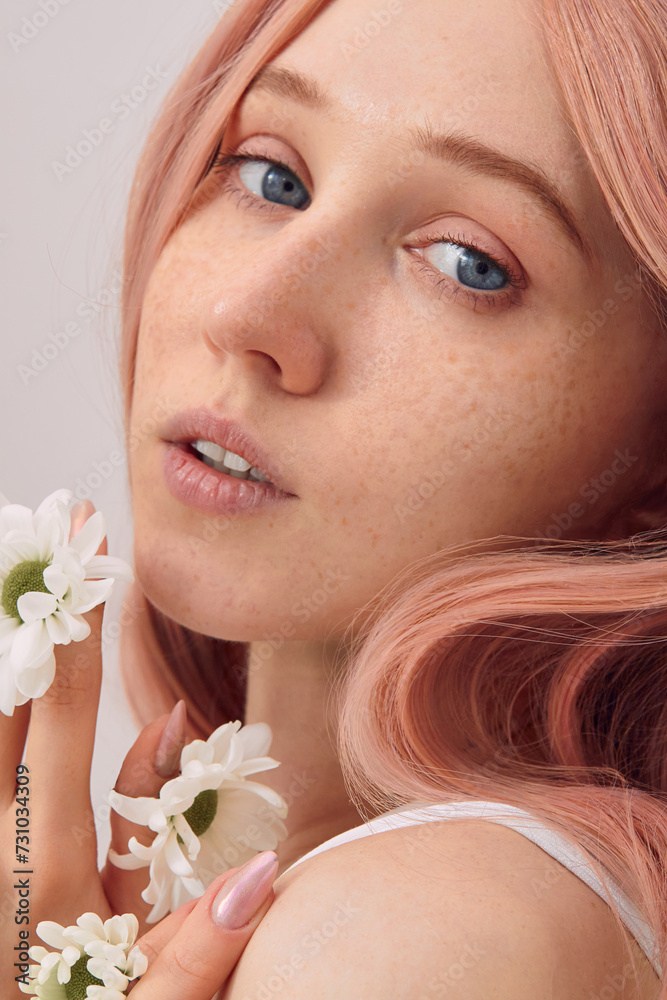 a young woman with chamomile flowers in a pink wig on a light background poses relaxed a young woman with chamomile flowers in a pink wig on a light background poses relaxed