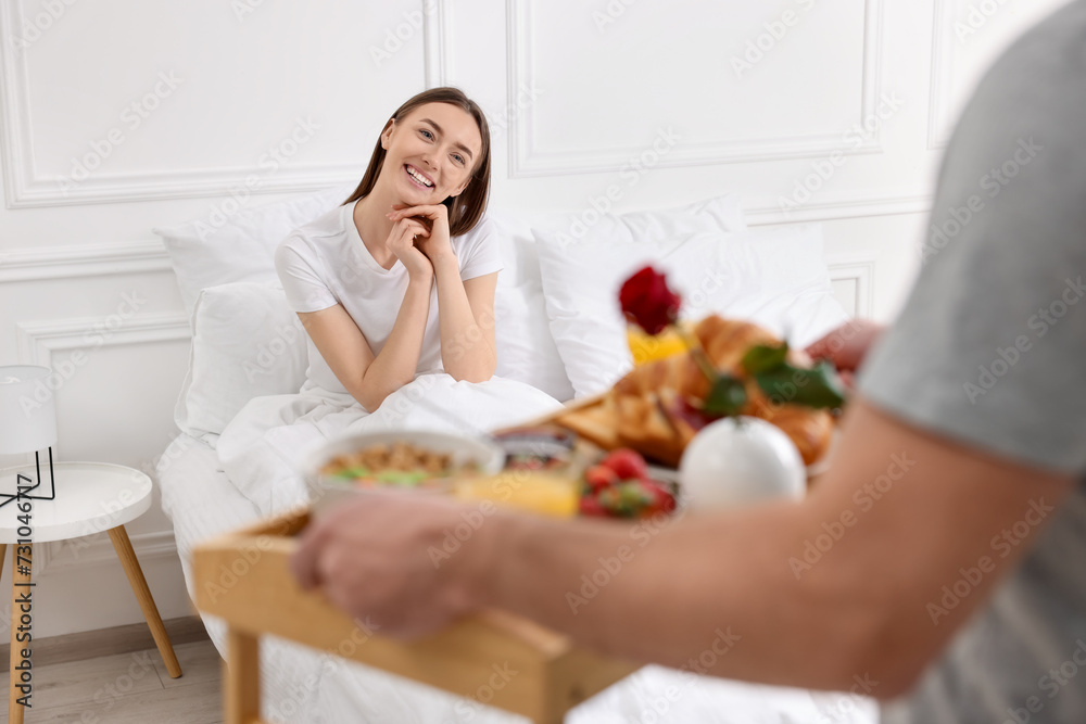 Romantic breakfast. Husband bringing tray with tasty food to his happy wife in bedroom, closeup