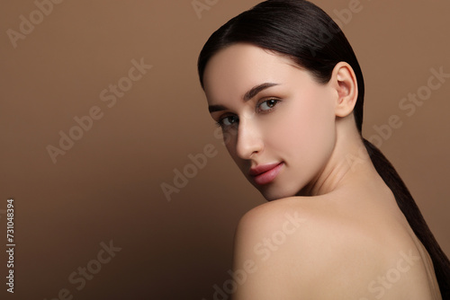 Portrait of beautiful young woman on brown background. Space for text