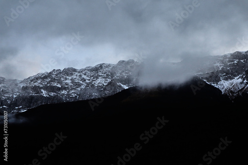 Primo piano di una montagna immersa da nuvole e un po' di neve