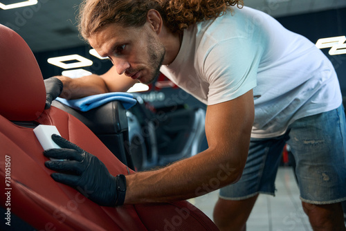 Male cleans a leather drivers seat with a melamine sponge
