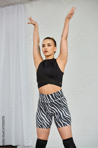 A graceful dancer in a striking outfit performs a dynamic choreography, while raising her hands