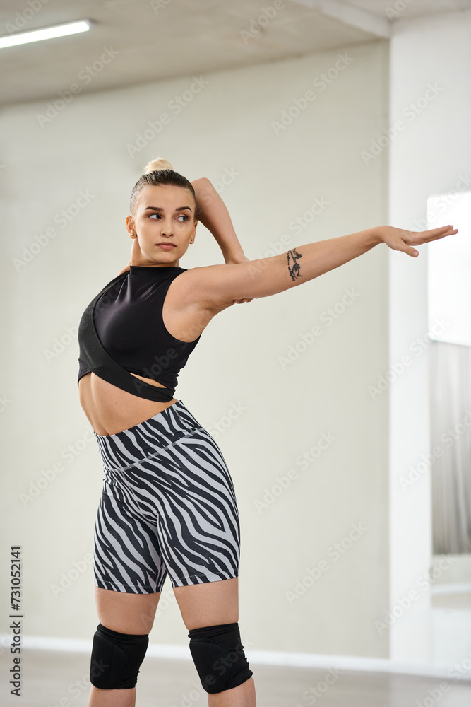 A graceful dancer stretches her body and arms in vibrant zebra shorts and a black top, flexibility