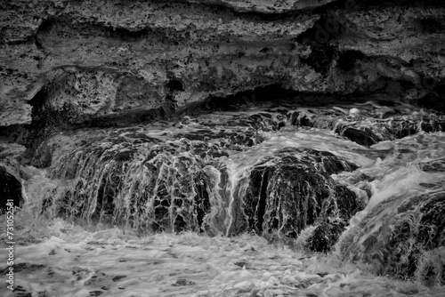 Schizzi di acqua che si infrange contro delle rocce photo