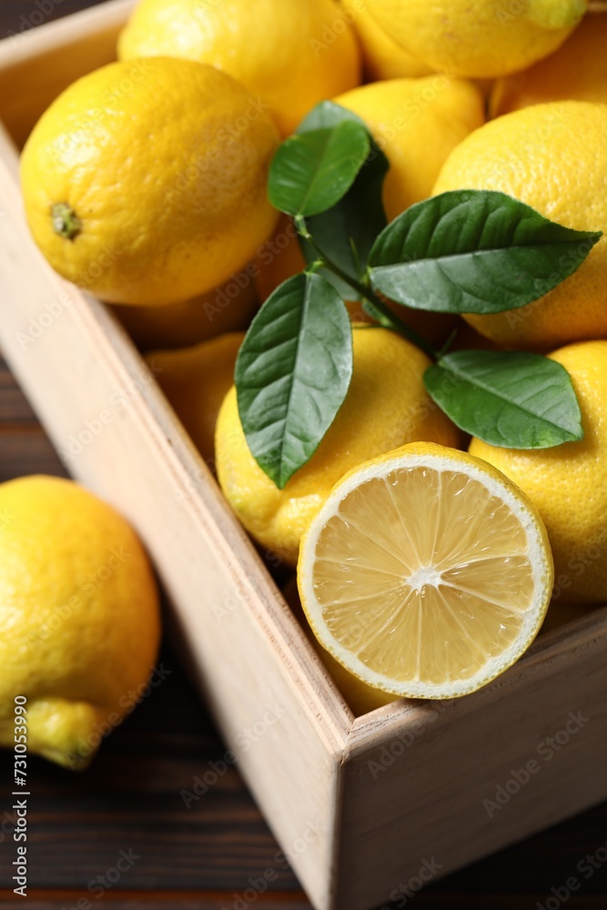 Fresh lemons in crate on wooden table, closeup