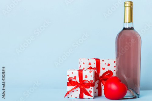 Bottle of wine on colored background for Valentine Day with gift box. Heart shaped with presrnt box perspective view with copy space photo