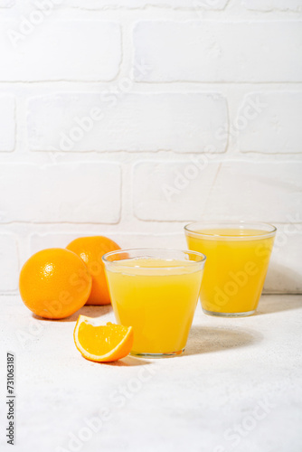 glasses of freshly squeezed orange juice on a white table, vertical