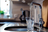 Pouring water, filling glass with water from tap in kitchen.