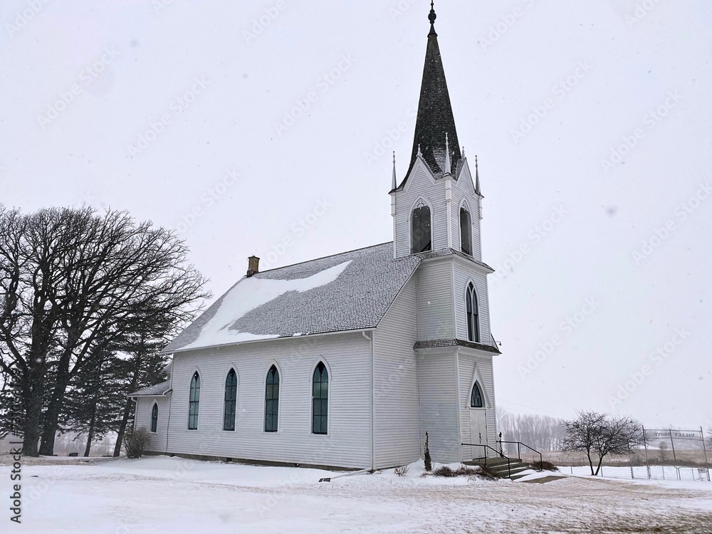 An old country church on a relaxing winter day during a snow fall