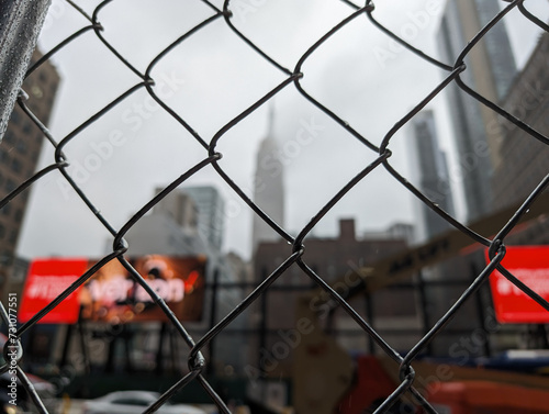 Image of a fence with the New York skyline in the backdrop.
