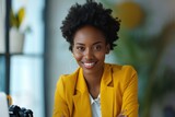 Beautiful African American businesswoman in yellow suit smiling at professional camera in office