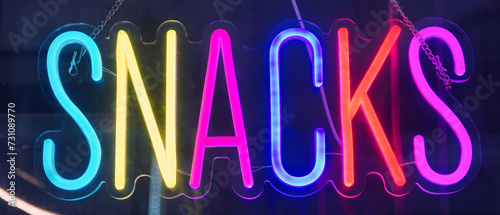 Neon sign in the form of a word SNACKS.