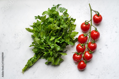 Fresh raw cherry tomatoes with bunch of parsley on a marble background, top v...