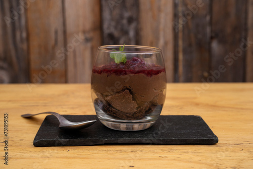Desserts. Closeup view of chocolate pudding with red berries puree, served in a glass. 