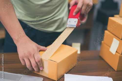 Hands of businessman sealing packages with tape at desk © waragron