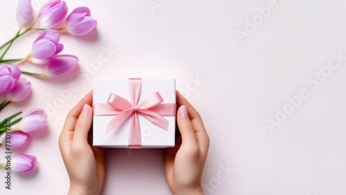 Banner with Woman hands holding elegant present white gift box with pink ribbon. Mother day, birthday, Valentine day. © ulkas