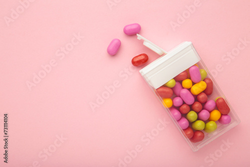 Canvastavla Tasty colored fruit dragee candies with box on pink background.