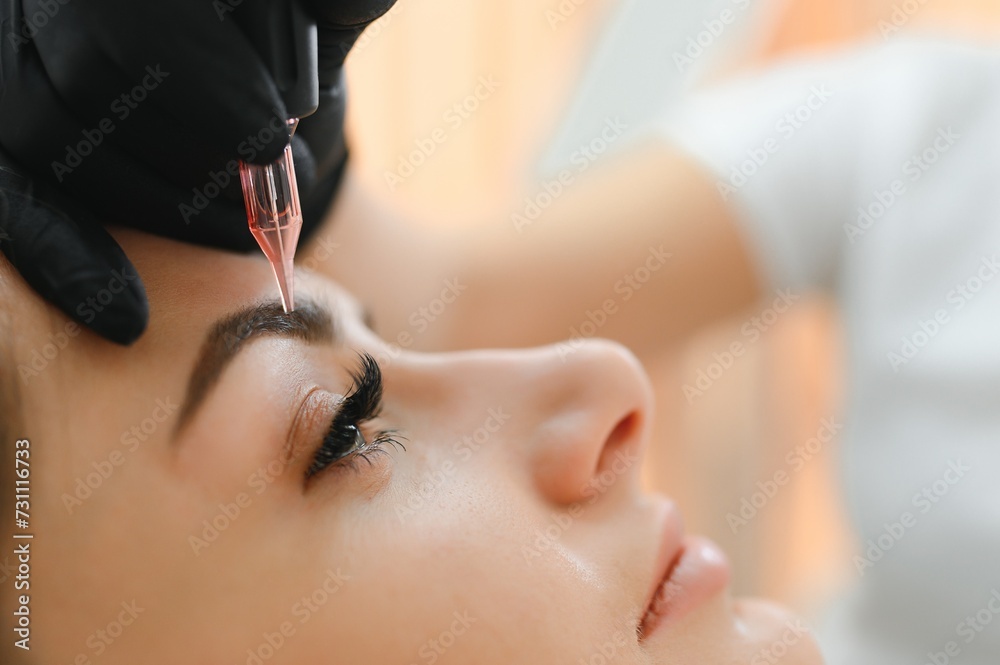 Process of creating permanent brow makeup with a machine at beauty salon - obrazy, fototapety, plakaty 