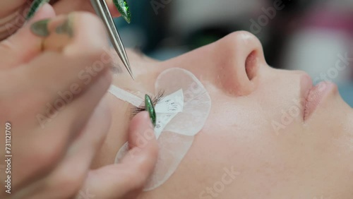 Close-up of eyelash extension procedure. Work process of a professional beauty technician lengthening women's eyelashes. False eyelashes. Eyelash extensions close-up.  photo
