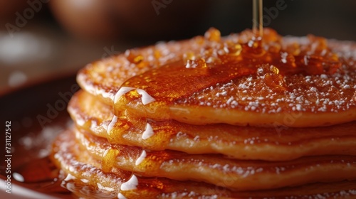 a stack of pancakes on a plate with syrup being drizzled on top of the pancakes and syrup being drizzled on top of the pancakes. photo