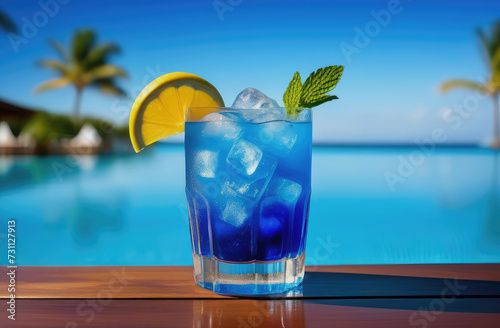 A cooling blue bright cocktail with ice cubes on the pool