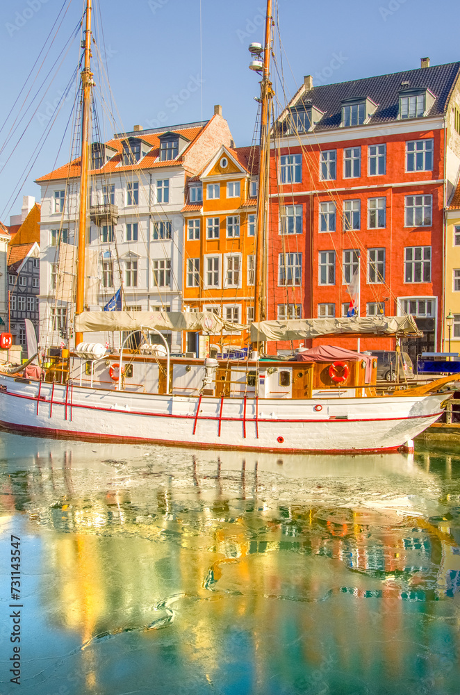 Colorful houses and white vintage sailboat in Nyhavn, Copenhagen most iconic sight for travelers. City with very low traffic, environmentally friendly and most sustainable destination in the world.