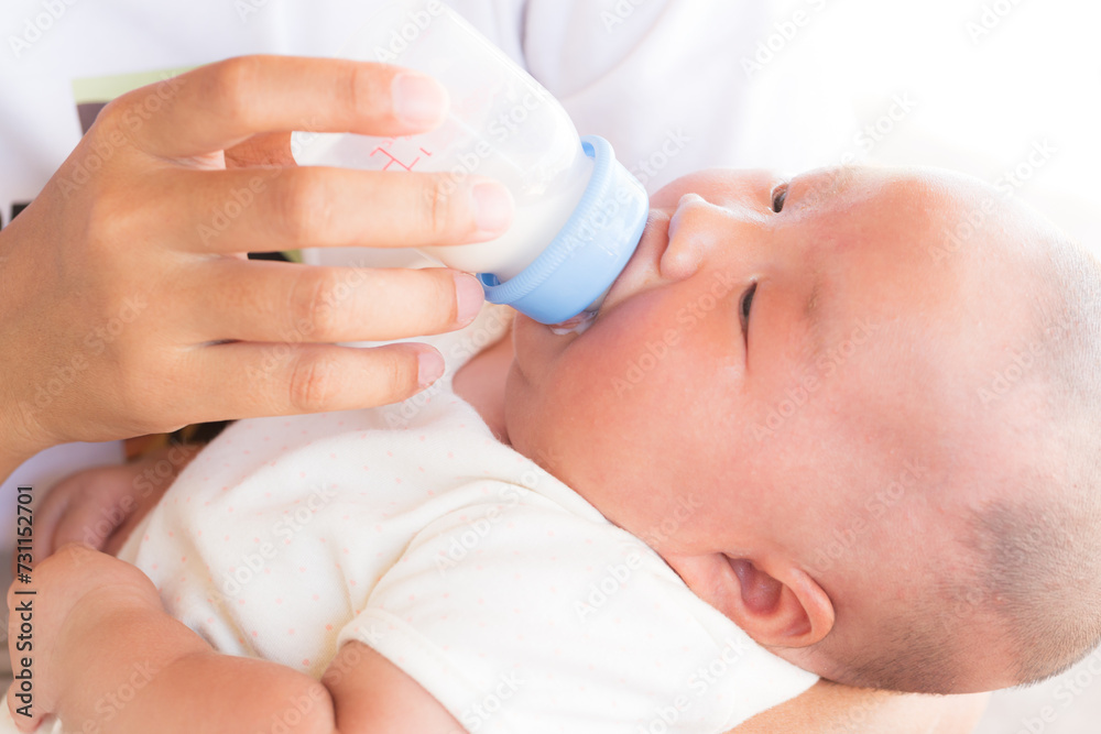loving mother feeding her little boy child with milk baby bottle at home, portrait infant Baby eating, drinking powdered milk, looking at camera loving mother feeding her little boy child with milk baby bottle at home, portrait infant Baby eating, drinking powdered milk, looking at camera
