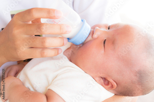 loving mother feeding her little boy child with milk baby bottle at home, portrait infant Baby eating, drinking powdered milk, looking at camera