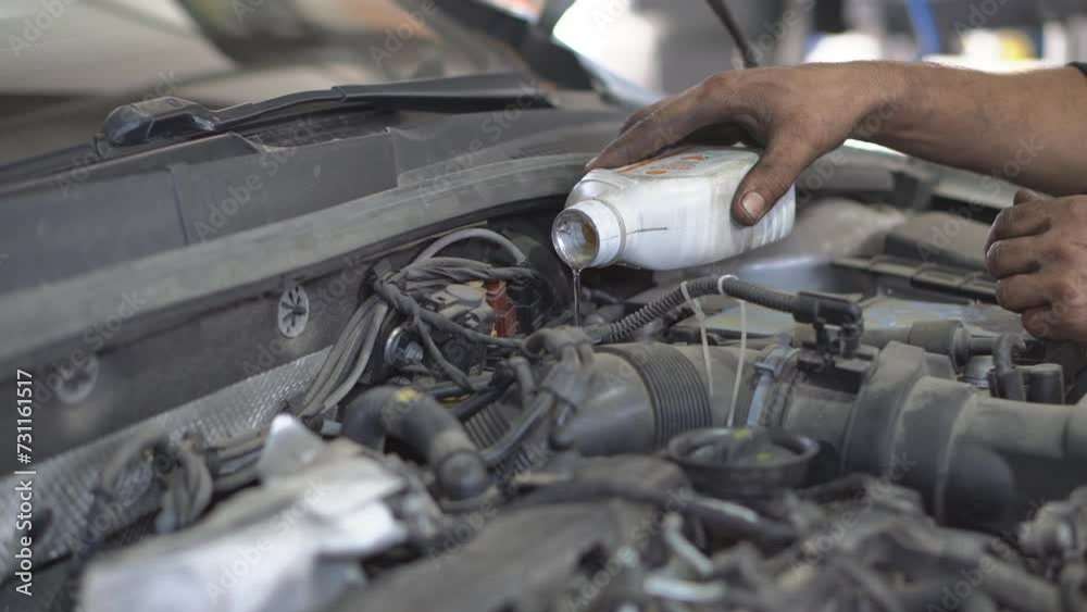 Pour motor oil into the car engine. Mechanic man pouring engine oil to car engine
