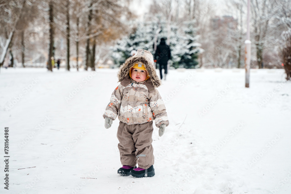 Cute child toddler walks in a snowy winter park Cute child toddler walks in a snowy winter park