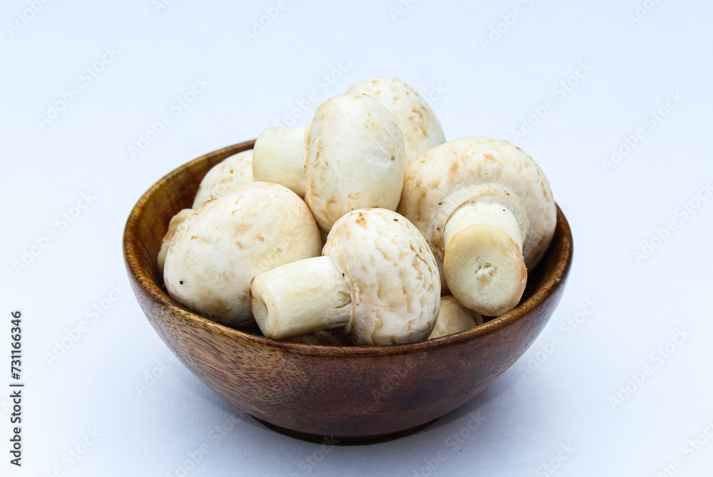 White mushrooms in a wooden bowl on white background White mushrooms in a wooden bowl on white background