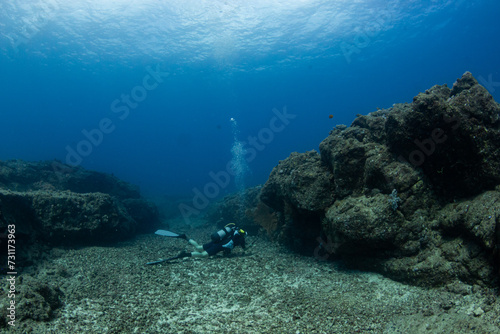 Fototapeta Naklejka Na Ścianę i Meble -  Female diver over rocky reef against blue background in Mauritius