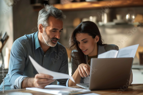 A couple looking at a paper with the month's bills and analyzing their finances