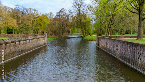 Stone embankment channels in the idyllic De Haar Castle park canal. Spring green trees. Utrecht, Netherlands.