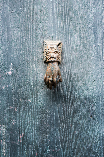 Old knocker on an old wooden door to the house.
