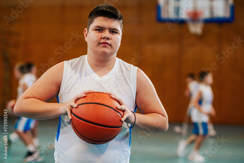 Portrait of a young basketball player with a ball on court having training.