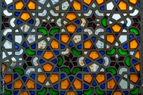 Perforated stucco window decorated with colorful stained glass with floral patterns on a building on the street in the resort town of Sharm El Sheikh, Egypt, closeup