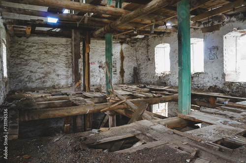 Interior of abandoned industrial building with wooden beams and brick walls in natural light