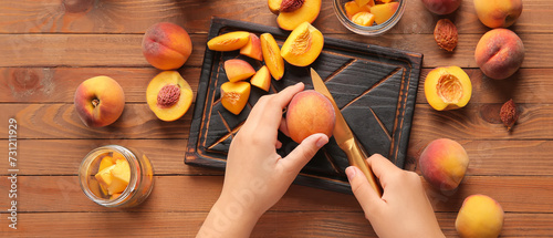 Woman preparing sweet peach jam on wooden background
