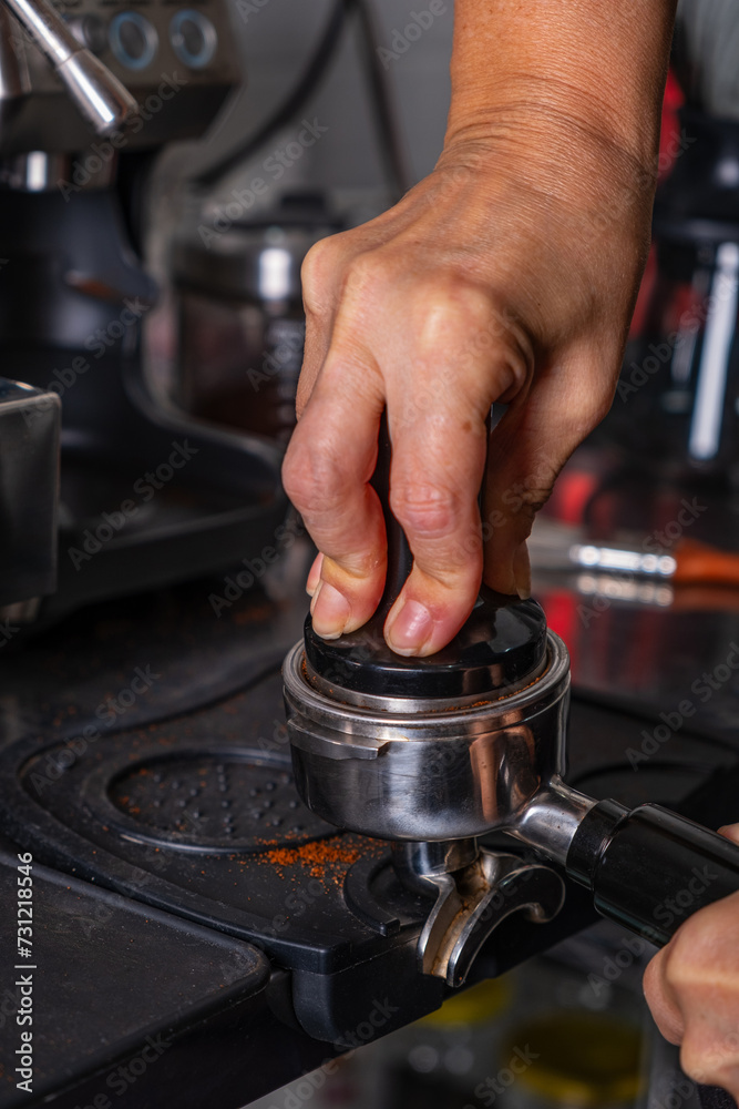 woman's hands pressing roasted and ground coffee to use in coffee maker